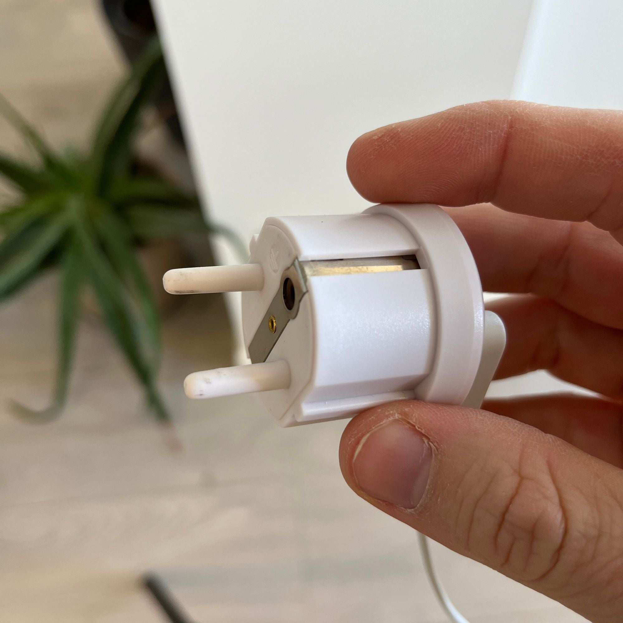 Close-up of a white country-specific grounding plug held in hand